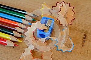 Coloured pencils, sharpener and shavings on wooden table.