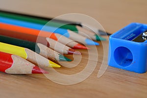 Coloured pencils and sharpener on wooden table.