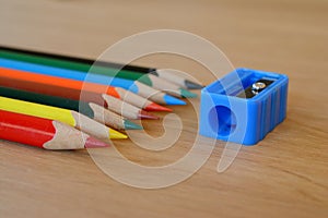 Coloured pencils and sharpener on wooden table.