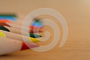 Coloured pencils on wooden table closeup.