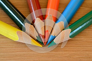Coloured pencils on wooden table closeup.