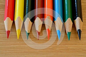 Coloured pencils on wooden table closeup.