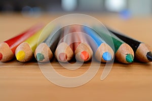 Coloured pencils on wooden table closeup.