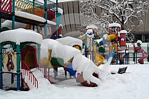 Coloured playground in winter, with modern building in background