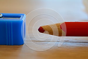 Coloured red pencil and sharpener on wooden table.