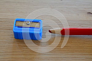Coloured red pencil and sharpener on wooden table.