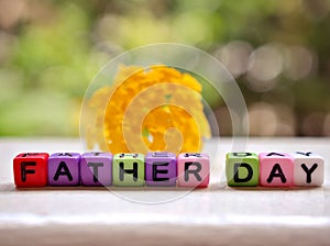 Colourful alphabet beads of happy Father`s day with yellow flower in garden pretty blurred, soft selective focus ,creative design