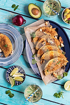 A colourful arrangement of crispy fish tacos with ingredients and sodas.