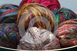 Colourful ball of recycled sari silk textile fibres from India, ready for spinning on a traditional spinning wheel as a hobby.