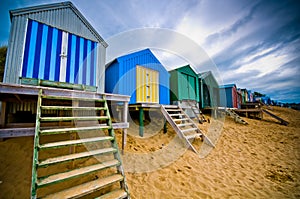 Colourful beach huts with dramatic sky