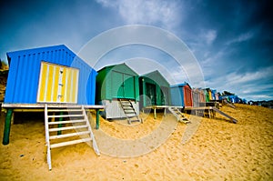 Colourful beach huts with dramatic sky