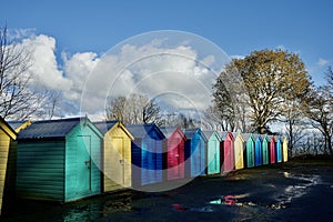 Colourful Beach Huts in a row under a blue sky.