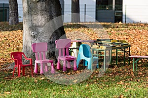 Colourful children`s chairs in an autumn garden