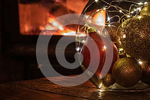 Colourful Christmas ornaments in front of cozy fire.