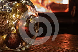 Colourful Christmas ornaments in front of cozy fire.