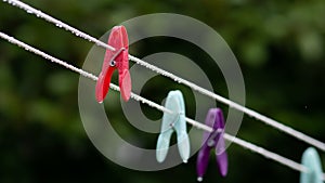 Close up of a red clothes peg on a line in the rain