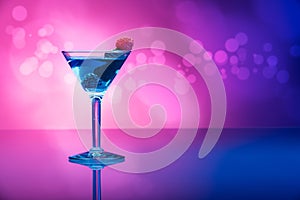 Colourful cocktails garnished with berries, background with light effects