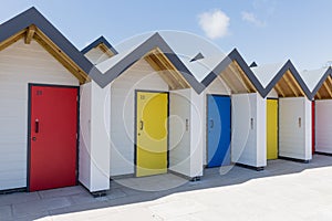 Colourful doors of blue, yellow and red, with each one being numbered individually, of white beach houses on a sunny day photo