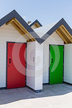 Colourful doors of red and green, with each one being numbered individually, of white beach houses on a sunny day