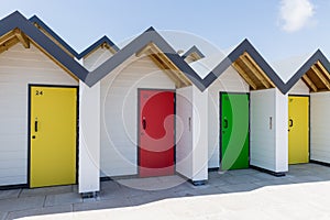 Colourful doors of yellow, green and red, with each one being numbered individually, of white beach houses on a sunny day