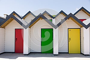 Colourful doors of yellow, red and green, , with each one being numbered individually, of white beach houses on a sunny day photo