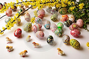 Colourful Easter eggs scattered beside a forsythia bush.