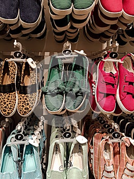 Colourful flat shoes in store display.
