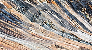 Colourful geologic striations and patterns on rock formation at bottom of glacier in Kvanefjord, Greenland