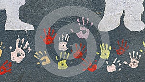 Colourful hands painted on a grey textured wall