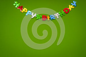 Colourful Happy Birthday greeting banner on a green wall in a celebration and party concept.