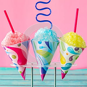 Colourful homemade fruit flavoured snow cones against a pink background. photo