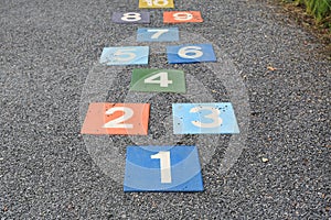 Colourful hopscotch playground markings numbers on stone at Pavement