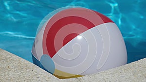 Colourful inflatable beach ball floating in shiny blue swimming pool