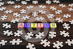 Colourful jigsaw puzzle and alphabet tiles with AUTISM word on wooden table