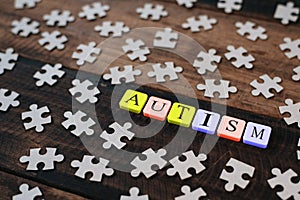 Colourful jigsaw puzzle and alphabet tiles with AUTISM word on wooden table