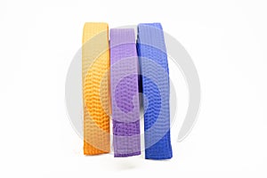 Colourful karate belt of yellow, purple and blue on white background photo