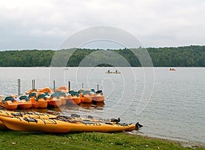 Colourful kayaks and rafts moored on sandy harbor of Phillipe Lake Quebec