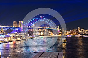 Colourful Light show at night on Sydney Harbour NSW Australia. The bridge illuminated with lasers and neon coloured lights