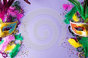 Colourful mardi gras beads, feathers and carnival masks on blue background with copy space