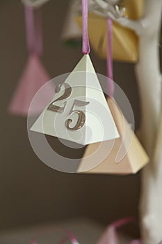 Colourful paper party decorations with the number twenty five with a silver finish, hanging on an painted white branch