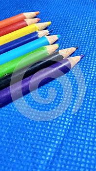 Colourful pencils ina row on the table blue background