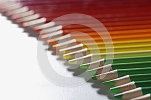 Colourful pencils set perfectly arranged in line on white surface