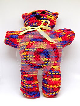 Colourful rainbow knitted teddy bear with ribbon scarf