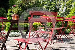 Colourful red bistro tables and chairs belonging at a cafe in a garden at Hartley Wintney, Hampshire, UK.