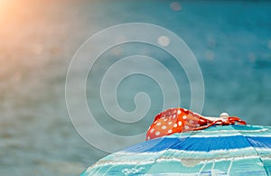 Colourful red and white bikini on an umbrella against the ocean beach with clear azure water. Relaxation, vacation idyllic