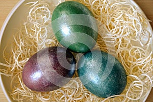 Colourful shiny easter eggs in the bowl with hay.