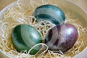 Colourful shiny easter eggs in the bowl with hay.