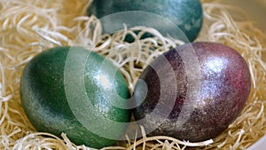 Colourful shiny easter eggs in the bowl with hay.