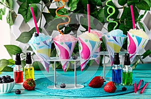 Colourful snow cones with crazy straws and flavoured syrups in front. photo
