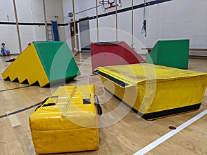 Colourful soft play equipment spread out across the gym floor with small boy in the background